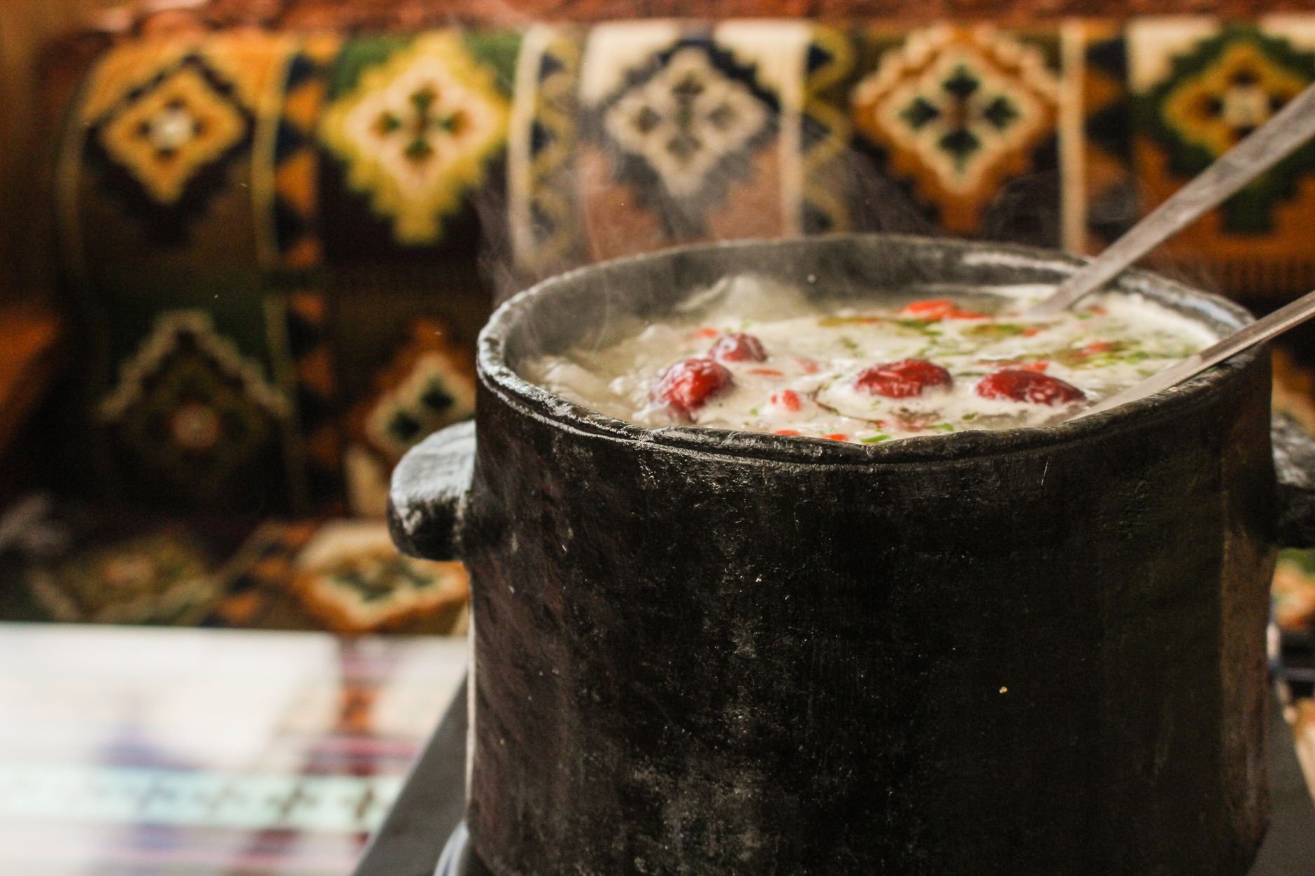 A steaming hot soup served in a rustic clay pot, exuding warmth and flavor.